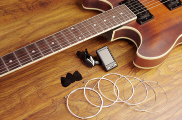 Wall Mural - Electric guitar, strings, tuner on a wooden textured table. 