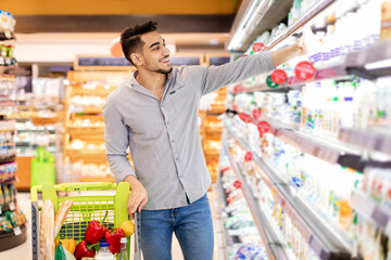 Wall Mural - Arabic Man Taking Milk Bottle Shopping Groceries In Supermarket