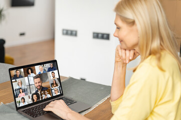 Morning meeting online. Senior woman is using app on pc for connection with colleagues, employees. Video call with many people together. Back view