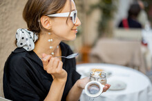 Woman eating tiramisu dessert at the restaurant outdoors. Concept of italian cuisine