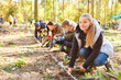 © Robert Kneschke - Group of volunteers and children planting a tree in the forest