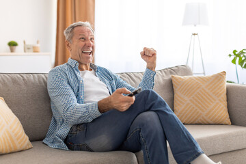 Excited senior man watching tv celebrating goal holding remote control