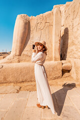 Wall Mural - A blogger girl takes photos in the ruins of the grandiose Karnak temple in the ancient city of Luxor in Egypt