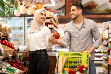 Wall Mural - Middle Eastern Spouses Doing Grocery Shopping Buying Vegetables In Supermarket