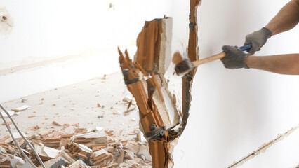 Man hitting a brick wall with a hammer, wall demolition