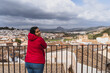 Chica joven con chaqueta roja mirando por un balcon en Antequera,pueblo andaluz