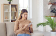 © Studio Romantic - Smiling young woman uses cellphone for messaging or for browsing social networks while relaxing at home on sofa. Woman checking social networks, using mobile app, shopping online or ordering delivery.