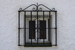 An old window covered by an ornate metal grill in the backstreets of the Spanish town of Estepona on the Costa del Sol