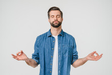 Caucasian Calm Relaxed Young Man In Casual Clothes Meditating, Doing Yoga Exercises, Stress Relief With Eyes Clossed Isolated In White Background