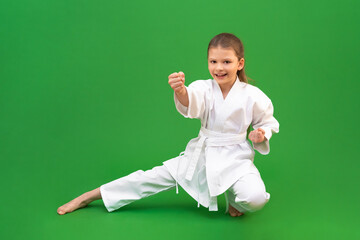 Wall Mural - A young girl trains in karate. Isolated on a green background,