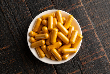 Wall Mural - Ground Turmeric Capsules form on a Wooden Table