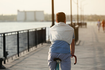 Wall Mural - Young man riding bicycle on embankment