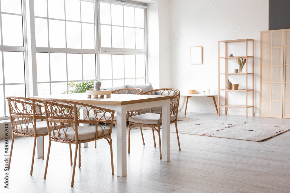 Interior of light dining room with table, sofa and shelving unit