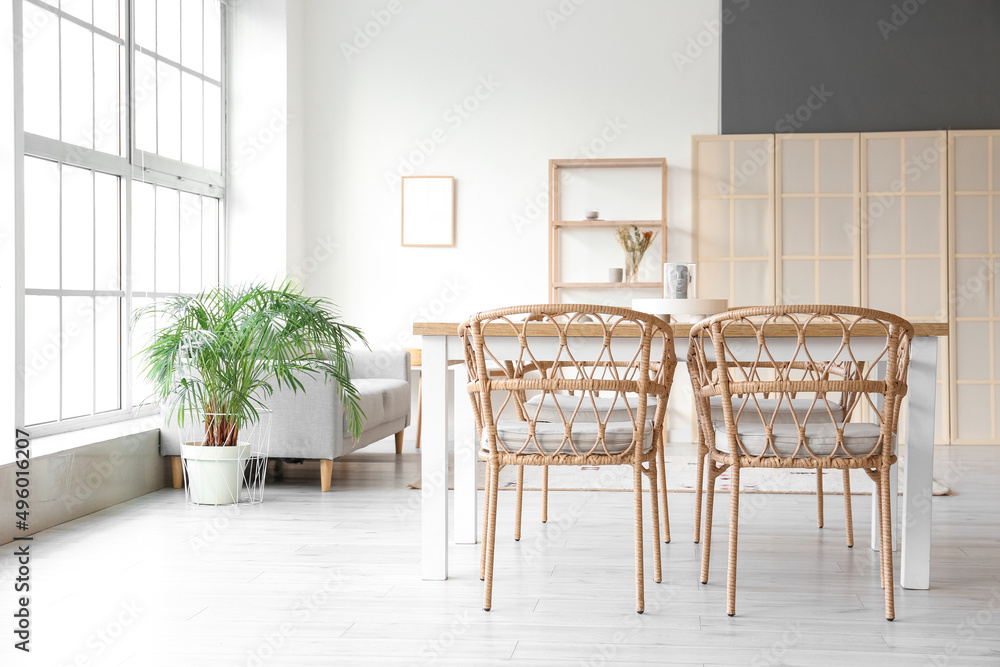 Interior of light dining room with table, sofa and folding screen