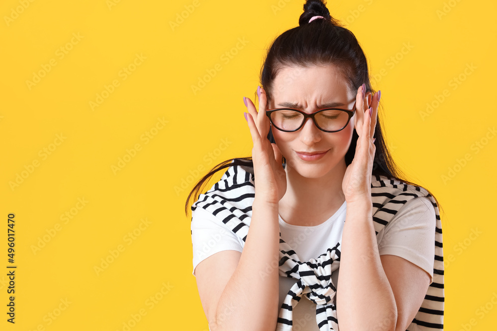 Worried young woman on yellow background