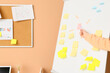 Woman pointing at sticky note on flipchart near beige wall