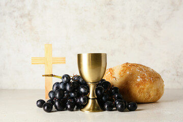 Wall Mural - Cup of wine with grapes, bread and cross on light background