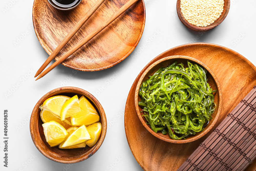 Plate with healthy seaweed salad and lemon slices on light background