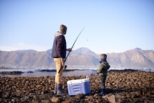 Lets Throw It In The Deep. Shot Of A Father And Son Standing With Their Fishing Gear By The Sea.