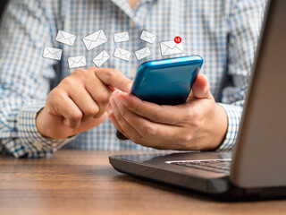 Wall Mural - businessman holding a smartphone receives a new message with email icons