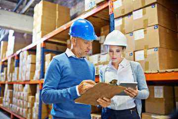 Poster - Putting their heads together to get it right. Shot of two people doing an inventory check in a warehouse.