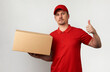 © Gecko Studio - Young delivery man in red uniform standing with parcel box