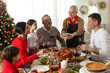 © New Africa - Woman with bowl of traditional Christmas kutia and her family during festive dinner at home. Slavic dish