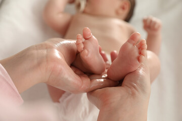 mother massaging her cute baby with oil, closeup