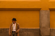 © WeeKwong - Portrait of adult man in hat and coat against yellow wall on street. Madrid, Spain