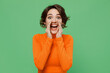 Young promoter woman 20s wear casual orange turtleneck scream hot news about sales discount with hands near mouth isolated on plain pastel light green color background studio People lifestyle concept.