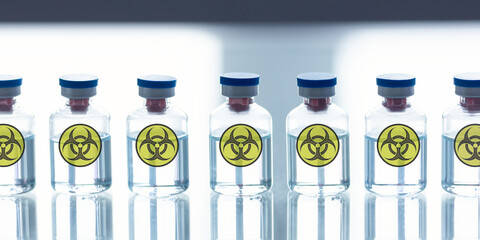 Prohibited development of warfare in a lab. A row of ampoules with a bio-hazard sign, close-up, selected focus.