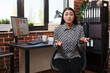 Unsure doubtful marketing company asian businesswoman shrugging arms while sitting at desk in office workspace. Questioning agency employee sitting in workplace while looking at camera.