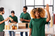 © Syda Productions - charity, donation and volunteering concept - happy smiling female volunteer waving hand and international group of people packing food in boxes at distribution or refugee assistance center