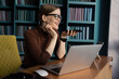 © muse studio - The receptionist is a woman with glasses working in a modern office using a laptop computer, coworking space online training