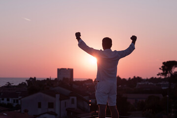 Wall Mural - an elderly businessman in casual clothes enjoys the roof of his house at sunset time. Selective focus 