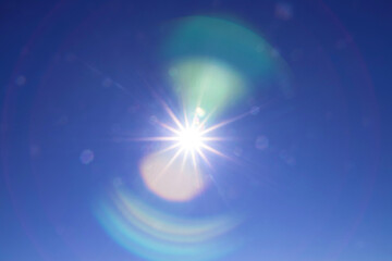 rainbow arcs glare from the bright sun on the blue sky. beautiful background to illustrate celestial