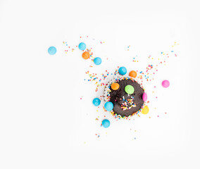 Wall Mural - Chocolate muffin in brown paper with colorful chocolate pieces isolated on white background, top view