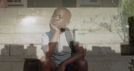 Wall Mural - Animation of cityscape over sad african american boy sitting on stairs