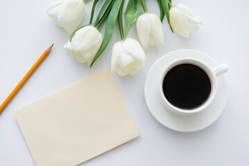 Canvas Print - top view of envelope with pencil near cup with coffee and tulips on white.