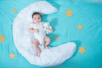 beautiful latin baby girl, two months old, lying on a white sheet in the shape of a moon and surrounded by golden stars, in the background a sea water blue sheet. concept of tenderness.