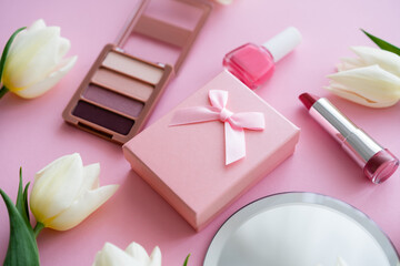 close up of white flowers, gift box and decorative cosmetics on pink.