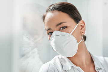 Canvas Print - 2020 The year of the face mask. Shot of a masked young businesswoman leaning against a window in a modern office.