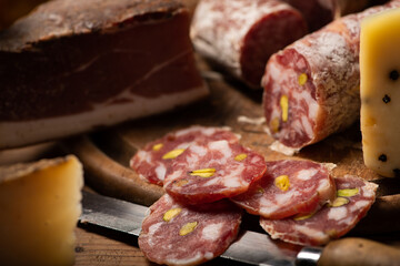 Cutting board with ham, salami, cheese, bread on a rustic wooden board