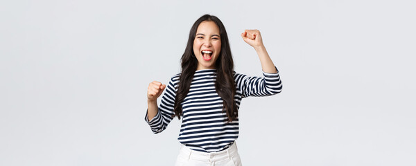 Wall Mural - Lifestyle, people emotions and casual concept. Excited happy asian woman attend sport competition, rooting and chanting for team, raising hands up and shout yes supportive