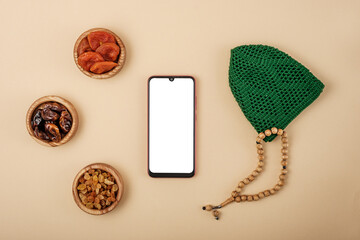 Wall Mural - Top view of smartphone with white screen, rosary lying next to dried fruits, religious concept, love of Islam, copy space, mock up