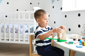 Poster - Cute little boy playing with wooden cubes at home