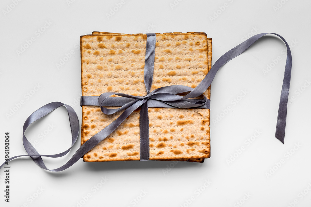 Jewish flatbread matza for Passover with ribbon on white background