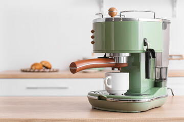 Modern coffee machine with cup on counter in kitchen