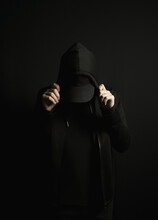 Man Standing Alone In The Dark Wearing A Black Hoodie And Hat