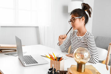 Wall Mural - Thoughtful little Asian girl during online lesson at home